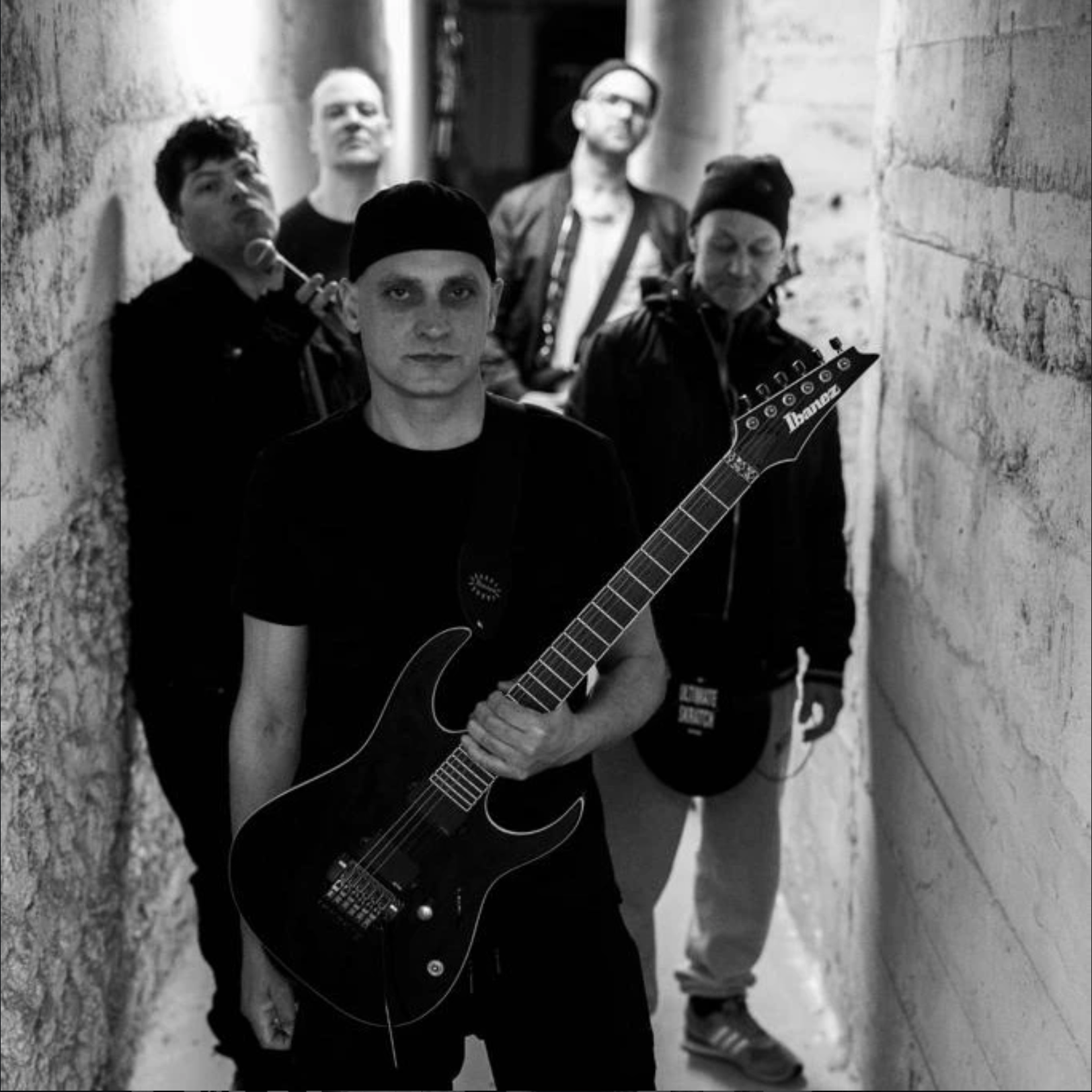 BROOK walking single file through a narrow corridor, guitarist in front